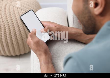 Mann, der in Innenräumen modernes Handy benutzt, selektiver Fokus Stockfoto
