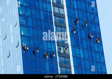 Hochhaus-Fensterreiniger, die an Seilen hängen und die Fenster eines Wolkenkratzers reinigen Stockfoto