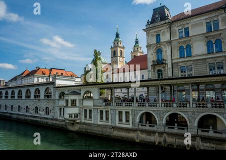 Blick auf den alten zentralen Markt entlang des Flusses Ljubljanica und die Kathedrale von Ljubjana im alten Ljubljana, Slowenien. Stockfoto