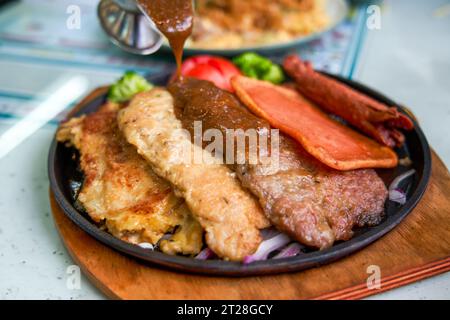 Ein köstliches und verführerisches, brutzelndes Steak, Huhn und Schweinekotelett in einem Teestaurant im Hong Kong-Stil Stockfoto