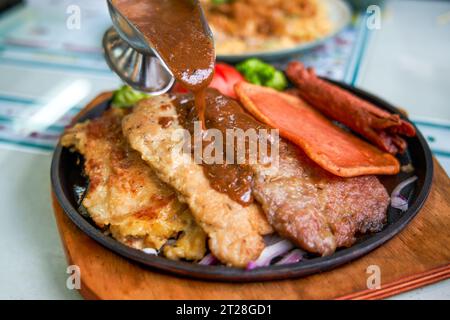 Ein köstliches und verführerisches, brutzelndes Steak, Huhn und Schweinekotelett in einem Teestaurant im Hong Kong-Stil Stockfoto