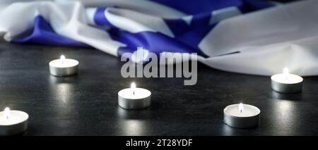 Brennende Kerzen und Flagge Israels auf dunklem Hintergrund Stockfoto