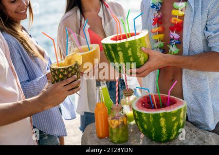 Trendige Gruppe von Freunden, die Cocktails auf der Party trinken. Junge Leute, die Spaß im Luxusresort haben. Stockfoto