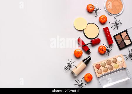 Lippenstifte und verschiedene dekorative Kosmetik mit Halloween-Dekor auf weißem Hintergrund Stockfoto