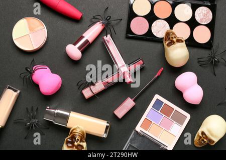 Lippenstifte und verschiedene dekorative Kosmetik mit Halloween Dekor auf schwarzem Hintergrund Stockfoto