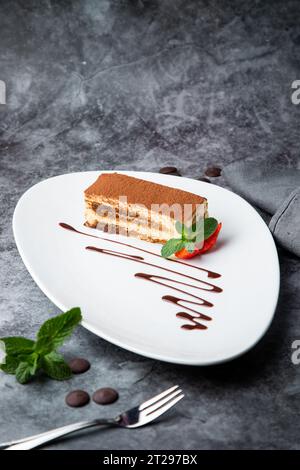 Biskuitkuchen gefüllt mit Erdbeeren, Minze und Schokoladensirup auf einer weißen Platte, Seitenansicht Stockfoto