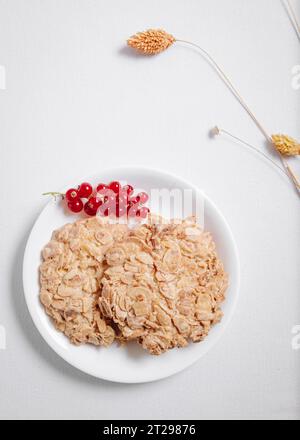 Vollkornkekse mit einem Zweig roter Johannisbeeren in einer kleinen weißen Platte von oben Stockfoto