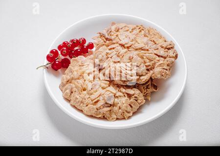 Vollkornkekse mit einem Zweig roter Johannisbeeren in einer kleinen weißen Platte, Seitenansicht Stockfoto
