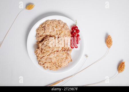 Vollkornkekse mit einem Zweig roter Johannisbeeren in einer kleinen weißen Platte von oben Stockfoto