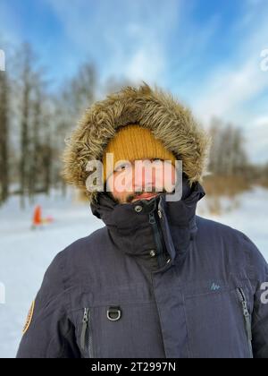 Porträt eines jungen kaukasischen bärtigen Mannes mit Parka und Kapuze am kalten Wintertag. Hochwertige Fotos Stockfoto