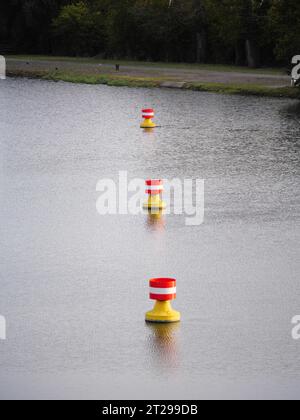 Rot-gelbe, weiße Bojen treiben in der Strömung auf der Wasseroberfläche eines Flusses Stockfoto