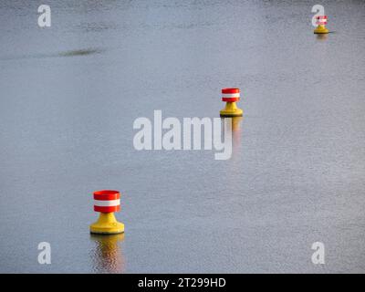 Rot-gelbe, weiße Bojen treiben in der Strömung auf der Wasseroberfläche eines Flusses Stockfoto