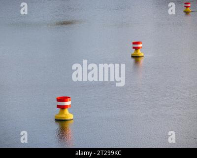 Rot-gelbe, weiße Bojen treiben in der Strömung auf der Wasseroberfläche eines Flusses Stockfoto