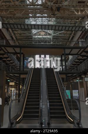London, Großbritannien - 13. Oktober 2023 - Blick auf zwei Rolltreppen im Inneren und einen alten Portalkran, der eine Kunstinstallation im New Battersea Power Station jetzt aufhebt Stockfoto