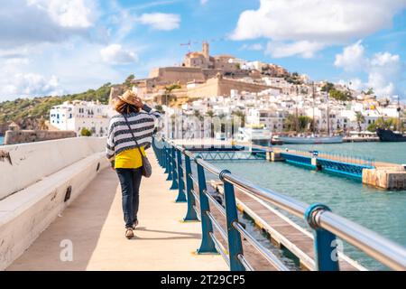 Eine junge Frau, die die Küstenstadt Ibiza im Winterurlaub von Al Faro auf den Balearen besucht Stockfoto