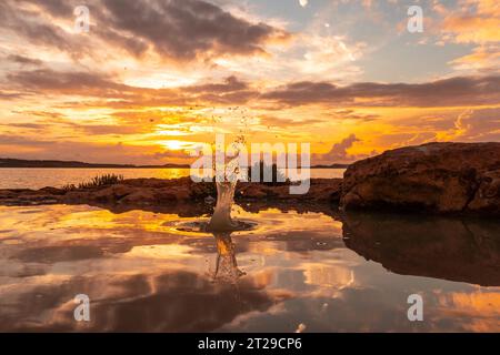 Wassertropfen nach dem Werfen eines Steins bei Sonnenuntergang auf San Antonio Abad, Ibiza Island Stockfoto