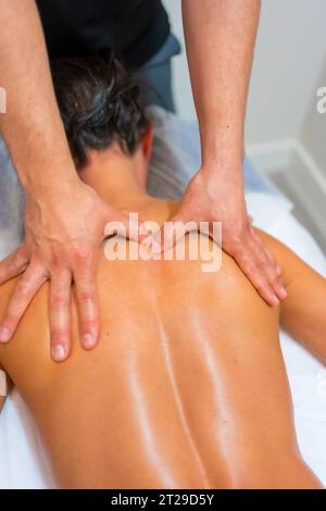 Physiotherapeutische Massage bei einer nicht erkennbaren Frau, die auf einer Liege auf ihrem Rücken liegt Stockfoto