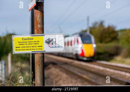 Achtung, schauen Sie in beide Richtungen, Warnschild am Bahnübergang der East Coast Mainline Railway. Stockfoto