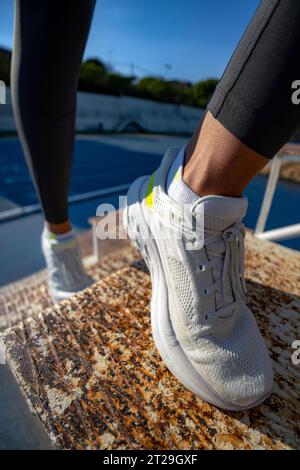 Nahaufnahme der weißen Laufschuhe einer athletischen Frau, die eine rostige eiserne Treppe klettert, um ihre Gesäßmuskeln zu trainieren. Stockfoto