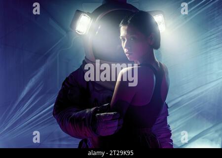 Ein Paar mit einem Mann im Anzug und einem Lichtstrahl und einer Frau in lässiger Kleidung, die im blauen Licht steht Stockfoto