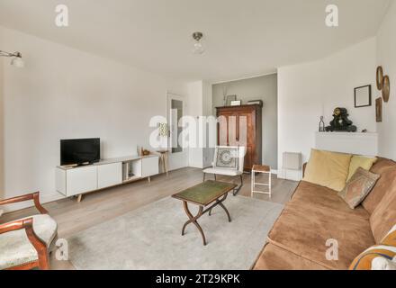 Innenraum des Wohnzimmers mit komfortabler Couch und Sessel mit Couchtisch und Fernseher in geräumigem Haus Stockfoto