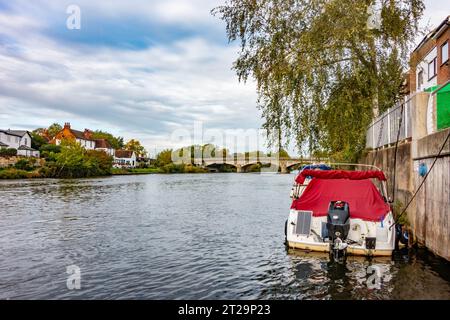 Blick entlang der Themse in Richtung Staines Bridge mit einem Motorboot, das am Ufer des Flusses in Surrey, Großbritannien, verankert ist Stockfoto