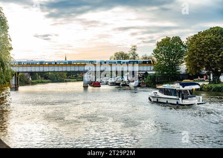 Ein Blick auf die Themse bei Staines-upon-Thames in Surrey, Großbritannien, in Richtung einer Eisenbahnbrücke, die den Fluss überspannt. Stockfoto