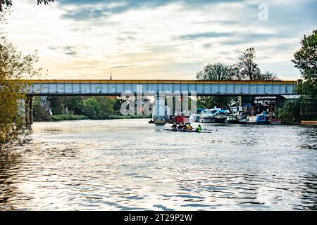 Ein Blick auf die Themse bei Staines-upon-Thames in Surrey, Großbritannien, in Richtung einer Eisenbahnbrücke, die den Fluss überspannt. Stockfoto