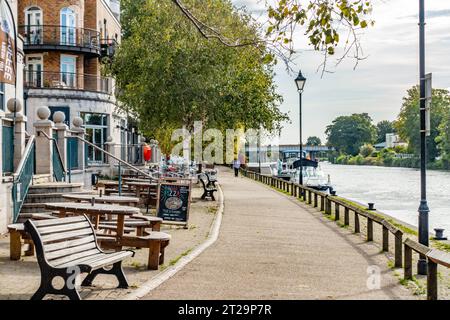 Blick auf die Themse bei Staines-upon-Thames vorbei am Slug and Saltuce Pub mit Tischen und Bänken draußen. Stockfoto