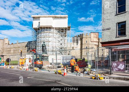 Straßenbauarbeiten vor Windsor Castle rund um die Bronzestatue von Königin Victoria. Die Gegend ist abgezäunt, während Arbeiter die Straße graben. Stockfoto