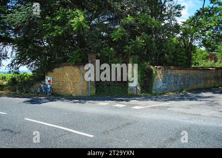 Alte schmiedeeiserne Tore in einem Mauerabschnitt in einer grünen und bewachsenen Ecke eines Schlossweinbergs, der von der Natur in Bagnols, Frankreich, zurückgewonnen wurde Stockfoto