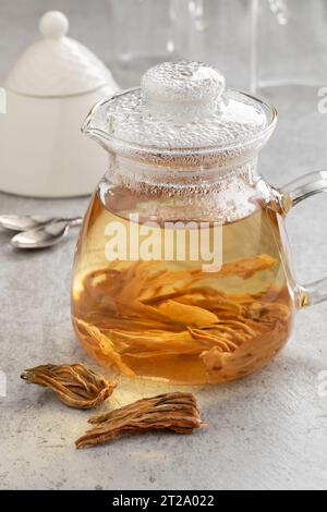 Glas-Teekanne mit weißen Hibiskusblättern und einem Haufen getrockneter Blätter vor der Nahaufnahme Stockfoto