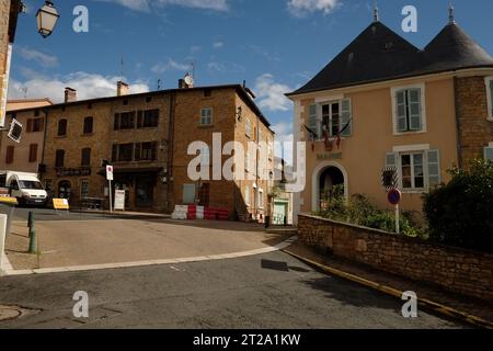 Alte Apartmenthäuser & Mairie des Dorfes Le Bois-dOingt, konisches Fliesendach, Steinturm und Fensterläden in der Auvergne-Rhône-Alpes, Frankreich Stockfoto