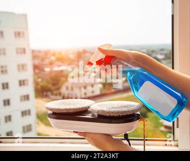 Sprühen von Reinigungsmitteln auf die Mikrofasern eines Fensterreiniger-Roboters vor Arbeitsbeginn. Stockfoto