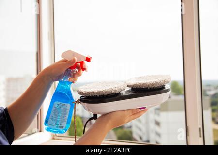 Sprühen von Reinigungsmitteln auf die Mikrofasern eines Fensterreiniger-Roboters vor Arbeitsbeginn. Stockfoto