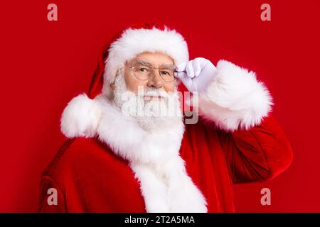 Foto von fröhlichen fröhlichen weihnachtsmann tragen weiße Handschuhe flauschige Pompon Neujahrskostüm Kamera isoliert auf rotem Hintergrund Stockfoto