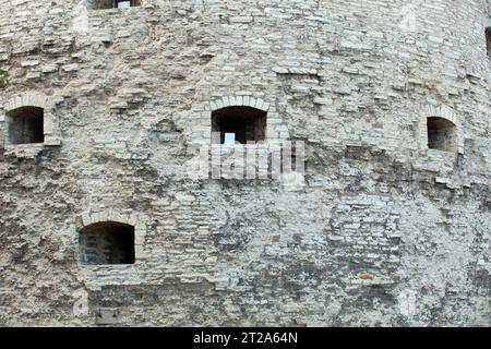 Gebrochene Steinstruktur an der alten grauen Wand mit Bogenfenster in Tallinn. Hintergrund. Vorlage. Für Design. Horizontal. Stockfoto