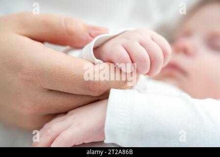 Unschuld und Vertrauen, das sich in der Hand des Babys an der Mutter zeigt. Das Konzept der heiligen Bindung von Geburt an Stockfoto