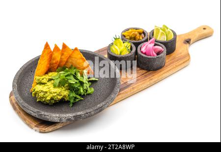 Avocado Dip Guacamole mit knusprigen Tortillas auf schwarzer Steinplatte auf weißem Hintergrund Stockfoto