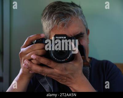 Ein Mann, der Fotos mit seiner spiegellosen Fujifilm-Kamera macht Stockfoto