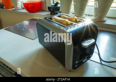 Ein Toaster mit Toastscheiben steht an sonnigen Tagen auf der Küchenzeile Stockfoto