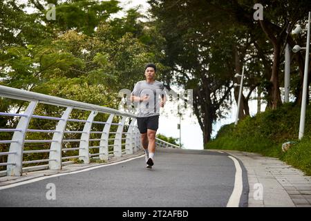 Junger asiatischer Mann, der draußen im Park joggt Stockfoto