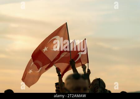 Izmir, Türkei, 9. September 2023, bei Sonnenuntergängen stehen vier Personen vereint und schwenken die türkische Flagge vor dem Hintergrund eines lebendigen Sonnenunterganghimmels Stockfoto