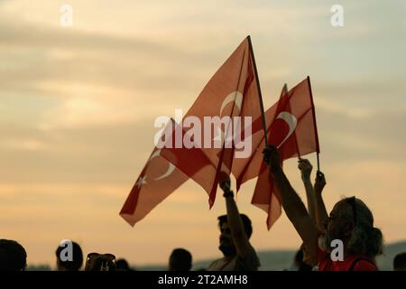 Izmir, Türkei, 9. September 2023, bei Sonnenuntergängen stehen vier Personen vereint und schwenken die türkische Flagge vor dem Hintergrund eines lebendigen Sonnenunterganghimmels Stockfoto