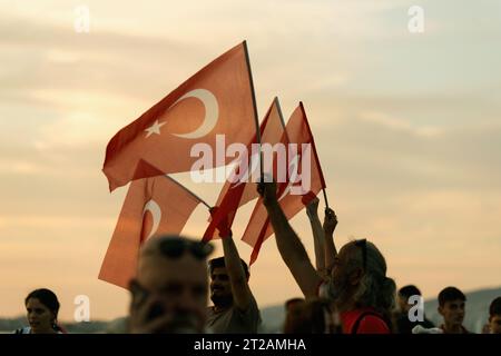 Izmir, Türkei, 9. September 2023, bei Sonnenuntergängen stehen vier Personen vereint und schwenken die türkische Flagge vor dem Hintergrund eines lebendigen Sonnenunterganghimmels Stockfoto