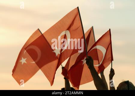 Izmir, Türkei, 9. September 2023, bei Sonnenuntergängen stehen vier Personen vereint und schwenken die türkische Flagge vor dem Hintergrund eines lebendigen Sonnenunterganghimmels Stockfoto