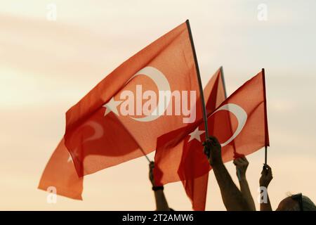 Izmir, Türkei, 9. September 2023, bei Sonnenuntergängen stehen vier Personen vereint und schwenken die türkische Flagge vor dem Hintergrund eines lebendigen Sonnenunterganghimmels Stockfoto