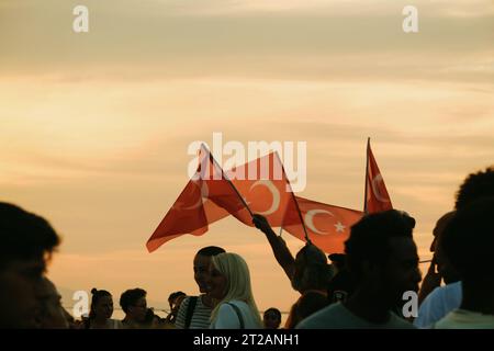 Izmir, Türkei, 9. September 2023, bei Sonnenuntergängen stehen vier Personen vereint und schwenken die türkische Flagge vor dem Hintergrund eines lebendigen Sonnenunterganghimmels Stockfoto