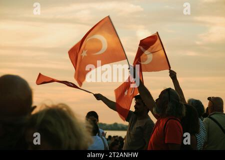 Izmir, Türkei, 9. September 2023, bei Sonnenuntergängen stehen vier Personen vereint und schwenken die türkische Flagge vor dem Hintergrund eines lebendigen Sonnenunterganghimmels Stockfoto