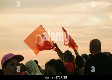 Izmir, Türkei, 9. September 2023, bei Sonnenuntergängen stehen vier Personen vereint und schwenken die türkische Flagge vor dem Hintergrund eines lebendigen Sonnenunterganghimmels Stockfoto